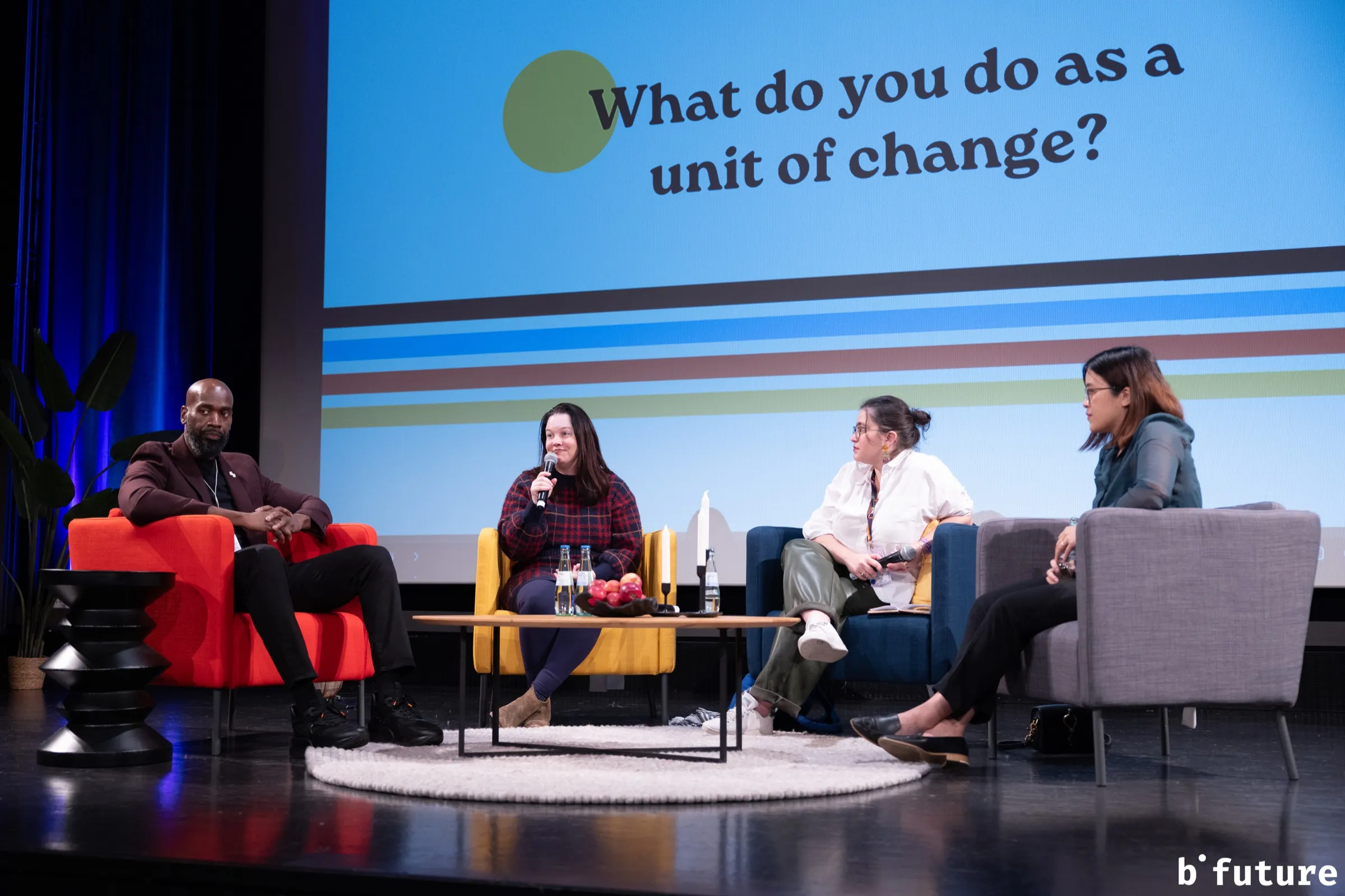 Méline Laffabry on a panel at the b° future festival, listening to another speaker, with the question "What do you do as a unit of change?" on the screen behind