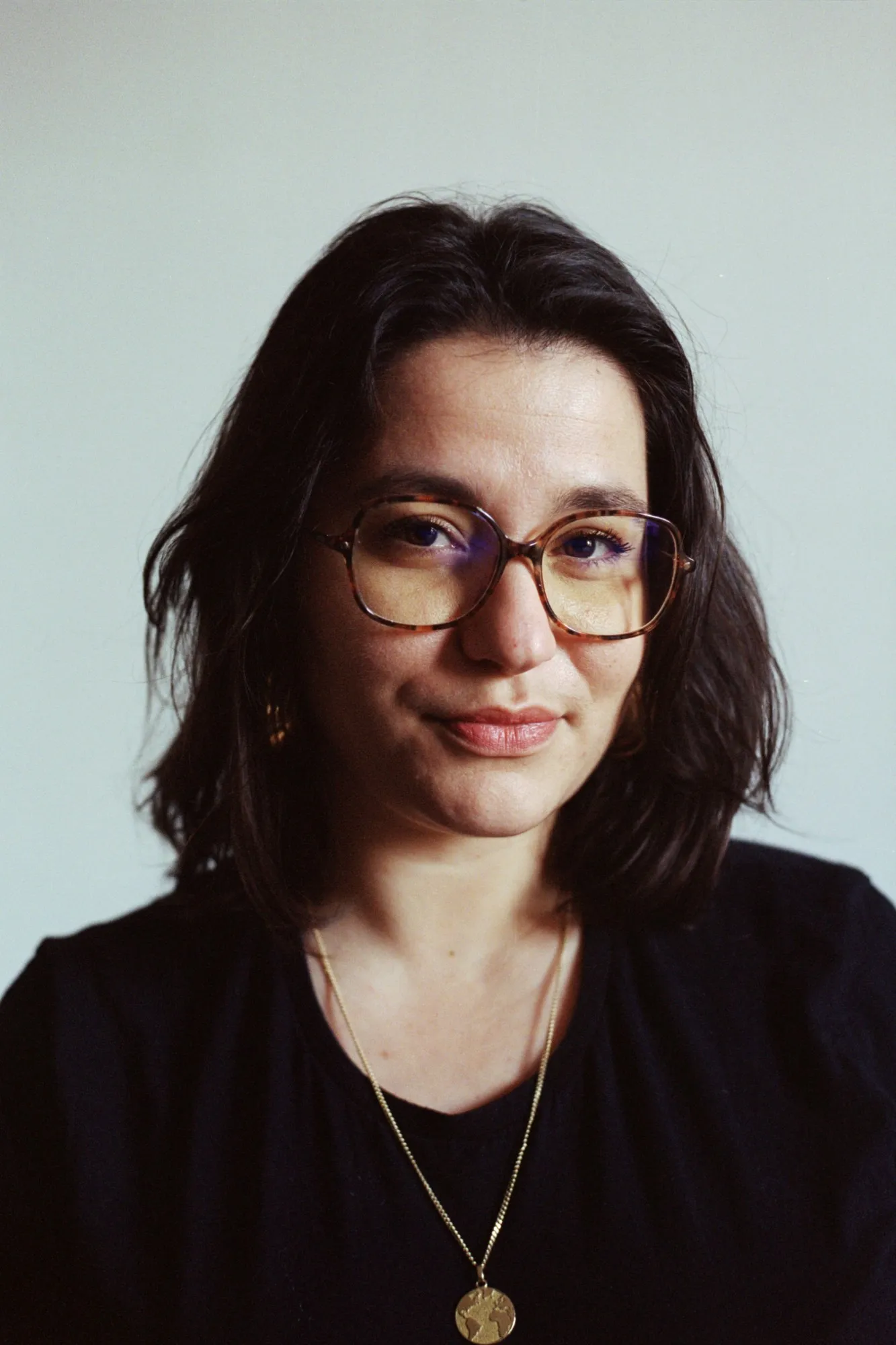 Méline Laffabry smiling, wearing tortoiseshell glasses and a gold pendant